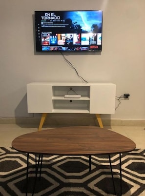 Un salon moderne avec un téléviseur à écran plat fixé au mur, qui diffuse une sélection de films.