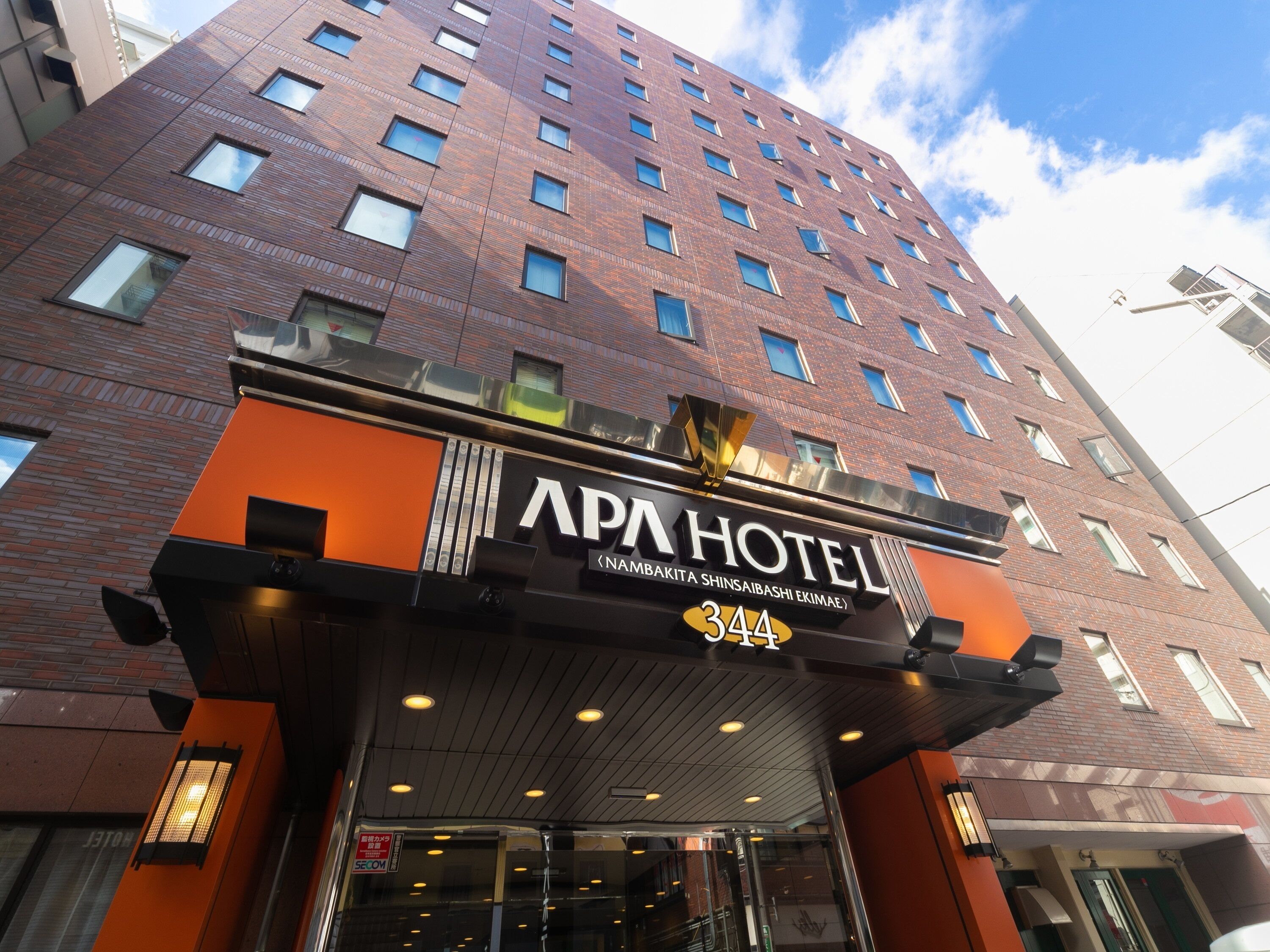 A hotel entrance with a sign reading "APA HOTEL" and the address "344".