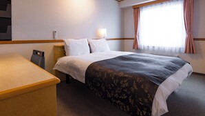 Une chambre d’hôtel avec un lit, une table de chevet, une lampe et une fenêtre avec des rideaux.