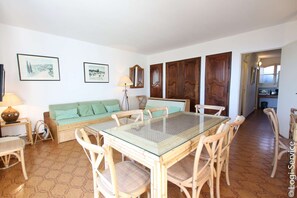 Un comedor con una mesa de vidrio, sillas de mimbre y un sofá con cojines.