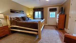A bedroom with a wooden bed, a wooden dresser, a nightstand, and a chair.