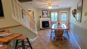 A dining area with a fireplace, wooden chairs, and a table.