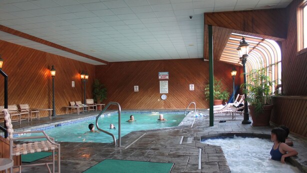 Una piscina interior con varias pistas, sillones de descanso y zona de hidromasaje.