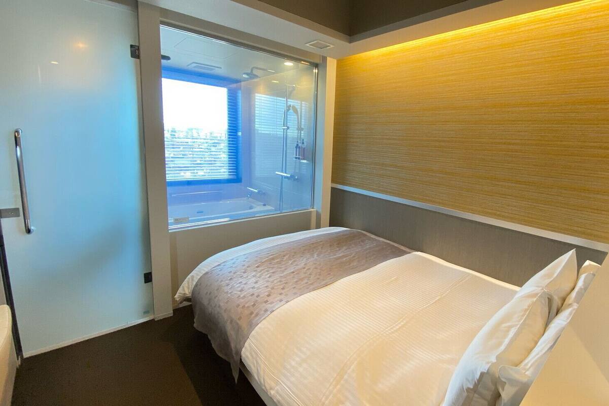 Een hotelkamer met een bed, een raam en een douche.