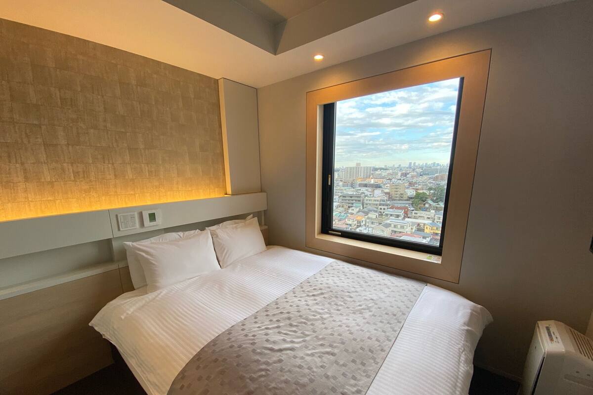 Een hotelkamer met een groot bed, uitzicht op een stadsgezicht door een raam en een ingebouwde verwarming.