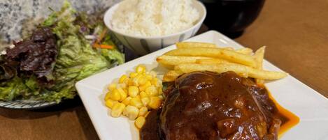 A plate with a meat patty, corn, fries, and a side salad.