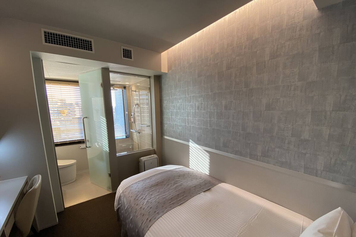 Een moderne hotelkamer met een bed, een bureau en een douche.