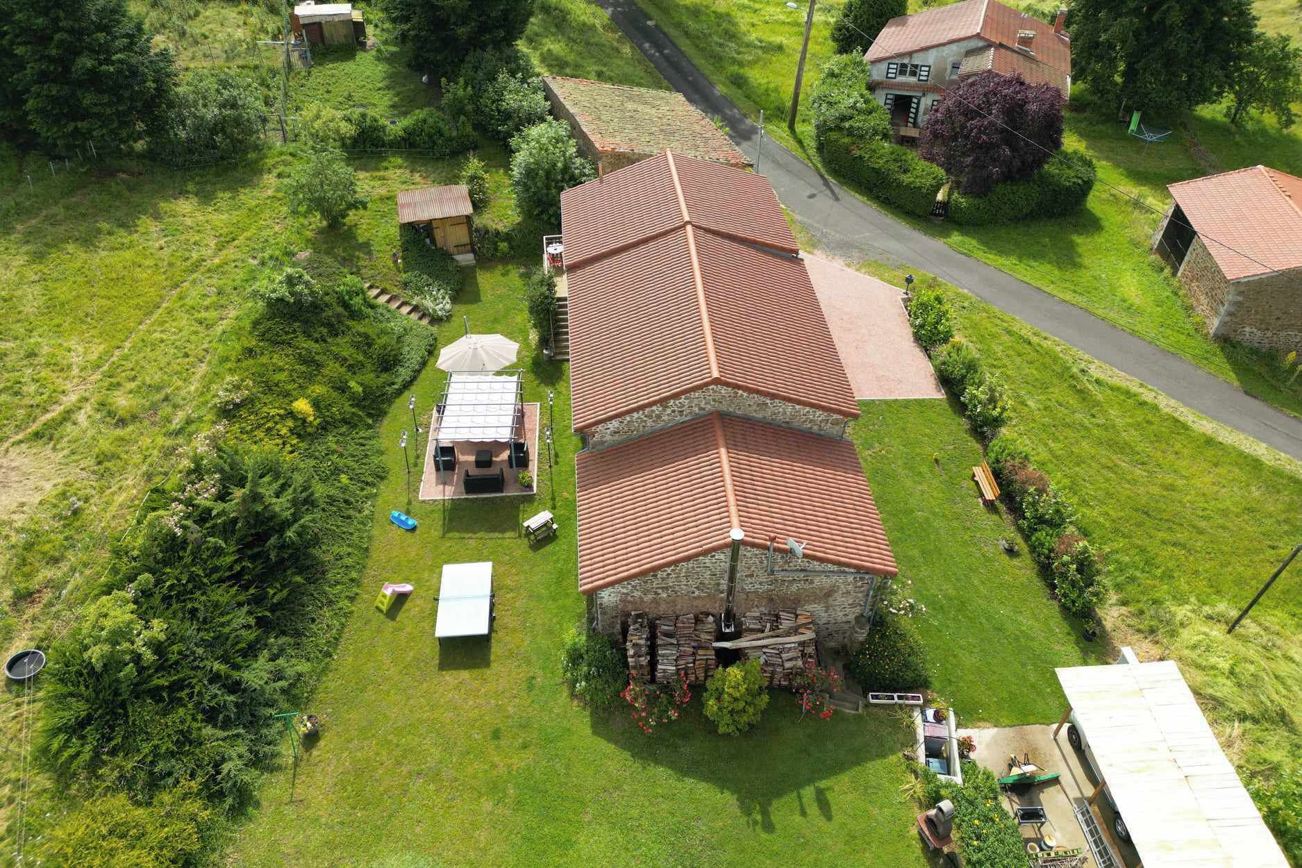 Un grande edificio a più piani con tetto in tegole rosse, immerso nel verde e con un piccolo stagno.