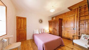 A bedroom with a wooden wardrobe, a bed with pink bedding, and a white chair. - Family suite on 2 levels in a peaceful hamlet. Ideal for families (LE VERNET LA VARENNE)
