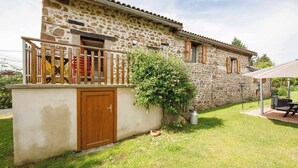 A stone building with a wooden door, a small balcony, and a garden area with a picnic table. - Family suite on 2 levels in a peaceful hamlet. Ideal for families (LE VERNET LA VARENNE)