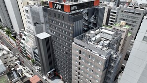 A multi-story building with a prominent 'APA' sign on the rooftop, surrounded by other high-rise buildings. - APA Hotel Ueno Ekimae (Tokyo)