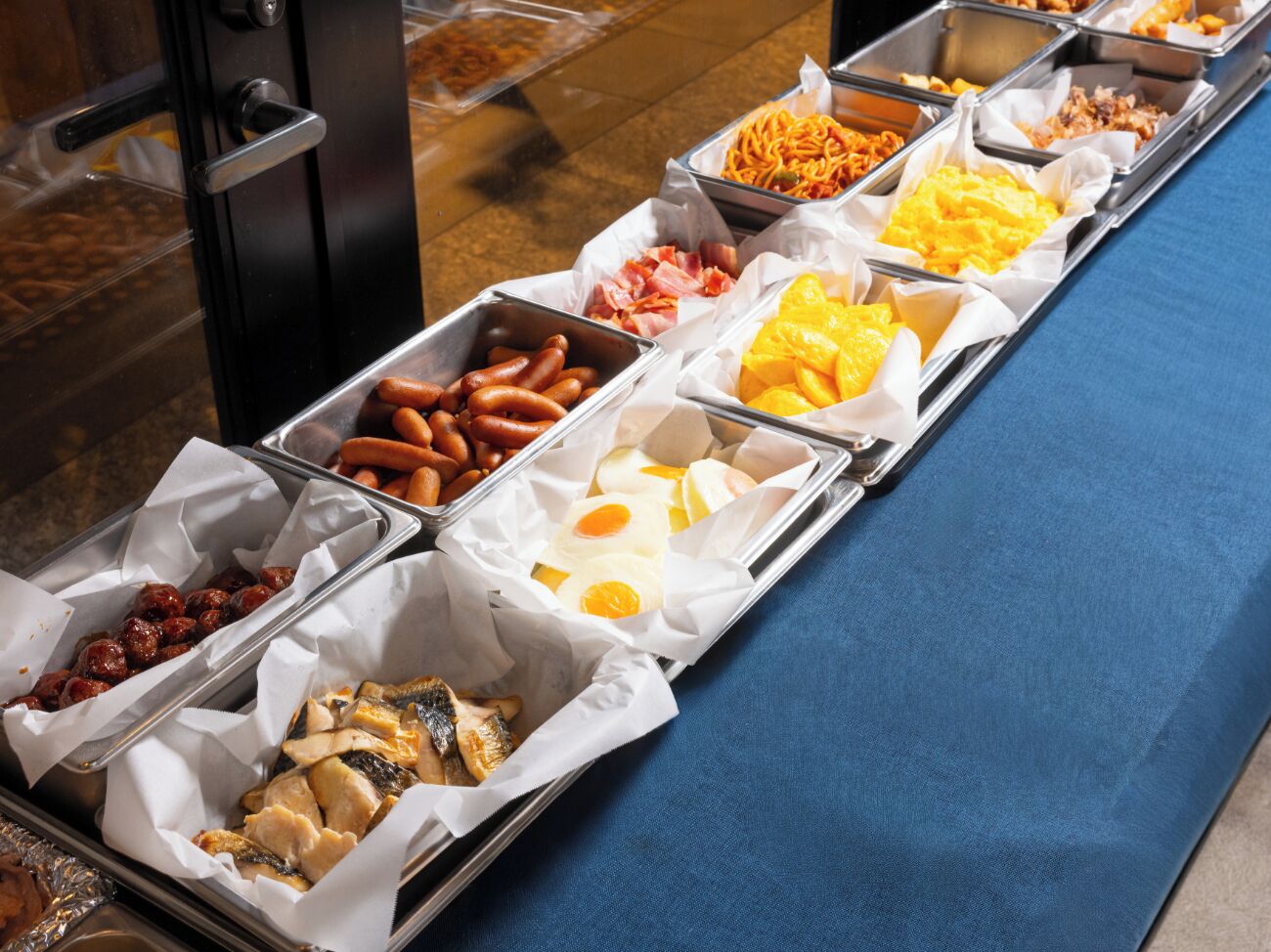 A buffet with various food items including sausages, eggs, and cheese.