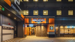 The exterior of APA HOTEL with a checkered pavement, a large entrance, and a sign indicating a parking area. - APA Hotel Ueno Ekimae (Tokyo)