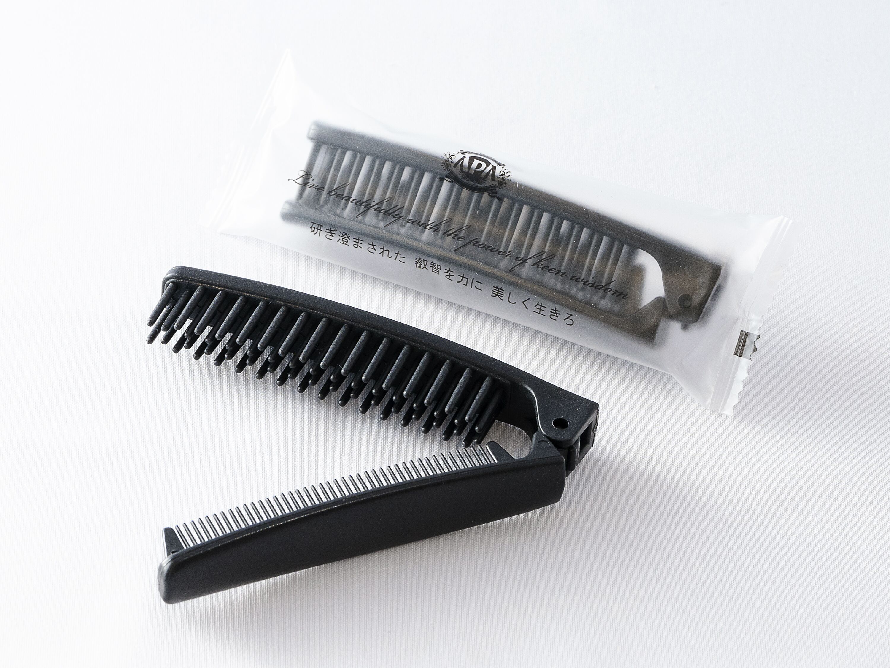 A black comb and a comb case with Japanese text.