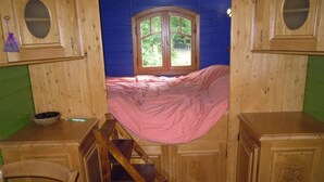 A room with a bed, a window, and wooden cabinets. - Roulotte Gite Tsigane A 15km DES Sables D'olonne (Grosbreuil)
