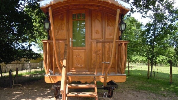 A wooden cabin with a front door, a porch, and a ladder leading up to the entrance. - Roulotte Gite Tsigane A 15km DES Sables D'olonne (Grosbreuil)