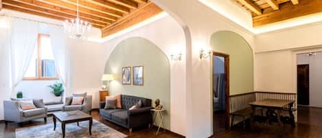 Amplia sala de estar con techo de madera alta, candelabro, conjunto de sofá, mesa de centro y mesa de comedor.