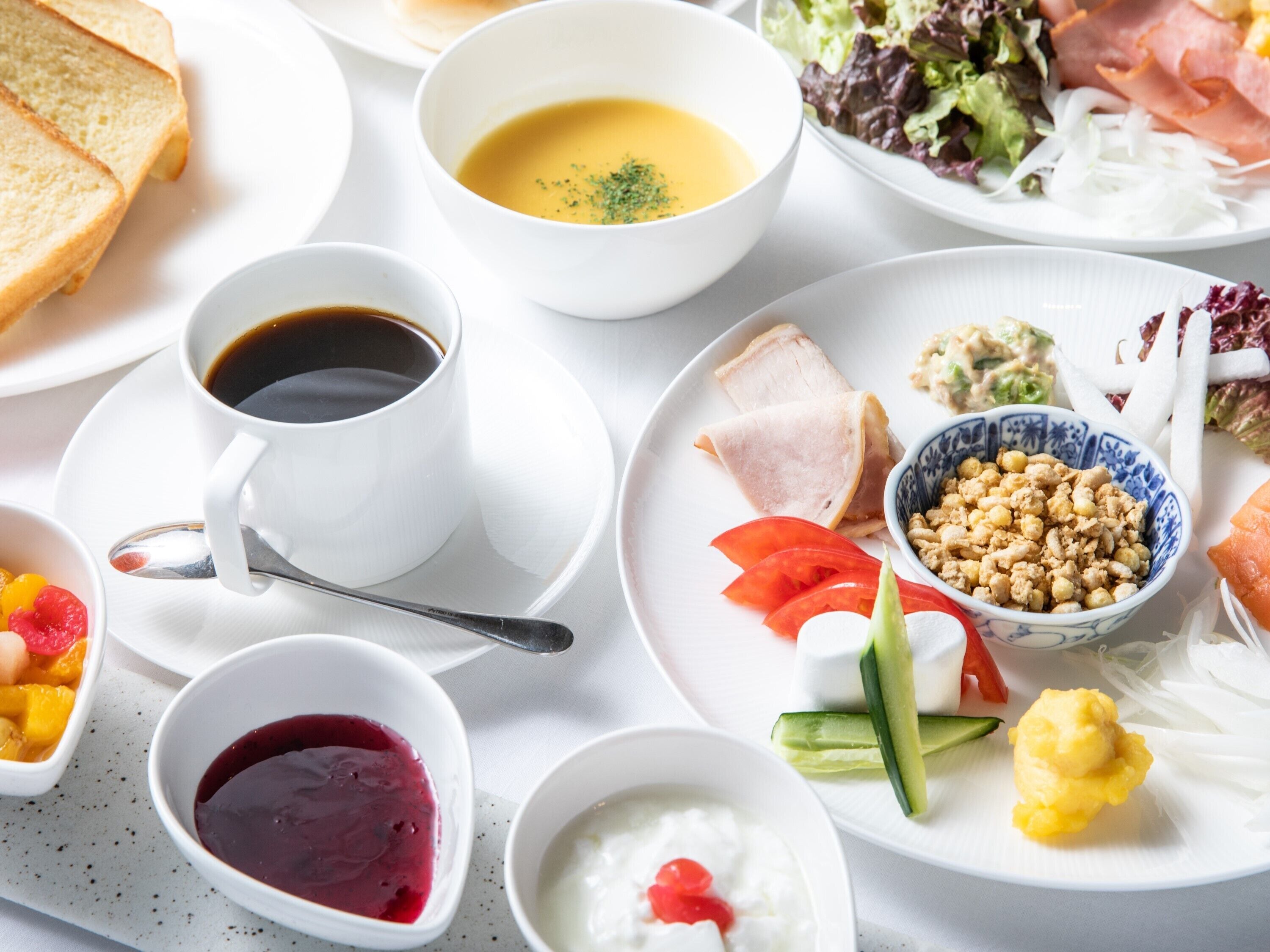 A table set with various dishes including soup, salad, meat, and fruit.