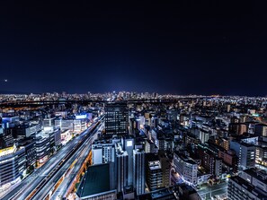 Une vue nocturne d’une ville, avec une zone urbaine dense, des bâtiments illuminés et une autoroute bien visible.