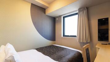 Une chambre d’hôtel avec un lit, un bureau, une fenêtre avec des rideaux et un luminaire au plafond.