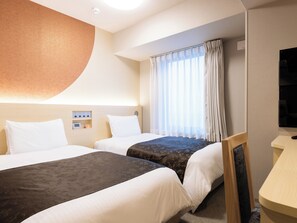 Une chambre d’hôtel avec deux lits, un bureau et une grande fenêtre avec des rideaux.