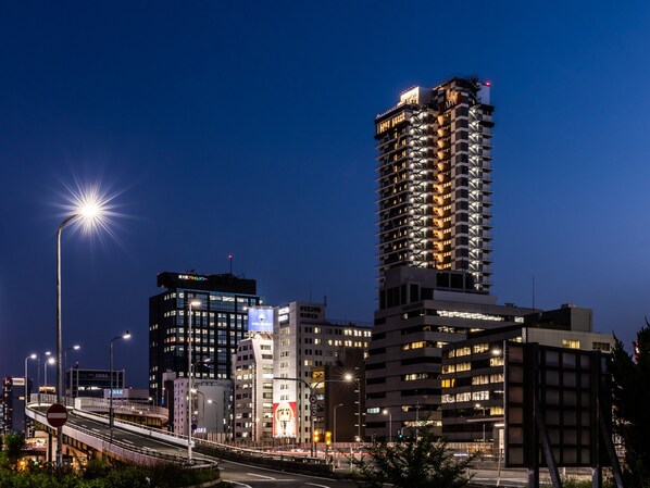 Un immeuble de grande hauteur, doté de nombreux étages, de fenêtres illuminées et d’une enseigne bien visible au sommet.