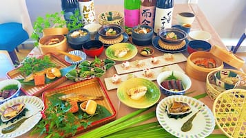 Taula preparada amb diversos plats, incloent sushi, sashimi i altres plats de cuina japonesa, acompanyats de diverses ampolles de sake.