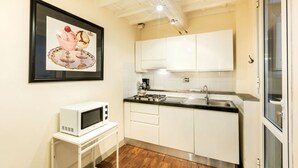 A compact kitchen with white cabinets, a microwave, a gas stove, and a sink. - Historic center⭐ Minutes to attractions, Train and River (Firenze)