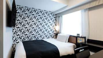 Une chambre d’hôtel moderne avec un grand lit, une table de chevet avec une lampe et une vue sur l’extérieur par une fenêtre.