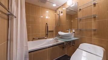 Un baño moderno con lavamanos con vidrio, una bañera y un inodoro.