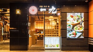 Entrada de restaurante com um quadro de cardápio e uma placa com caracteres japoneses.