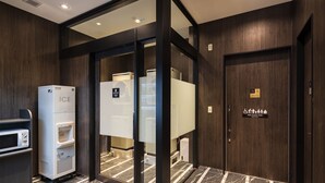Uma casa de banho de hotel moderna com dispensador de gelo autónomo, sanita multifunções e chão em mosaico de mármore.