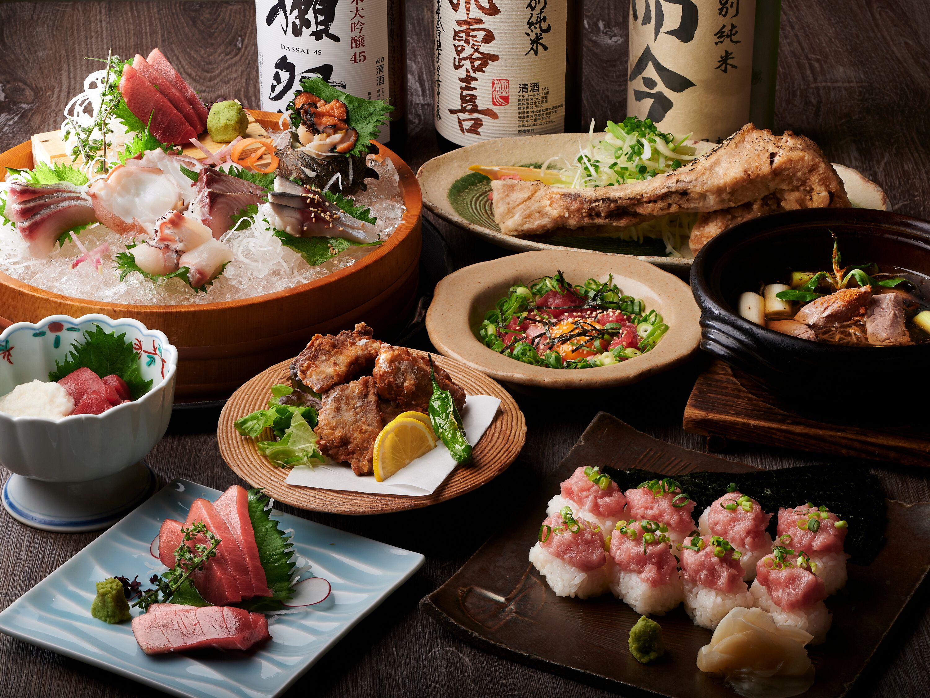 A variety of Japanese dishes including sashimi, sushi, and a bowl of soup.