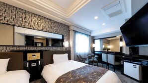 Quarto de hotel com duas camas, uma escrivaninha, televisão e minibar.