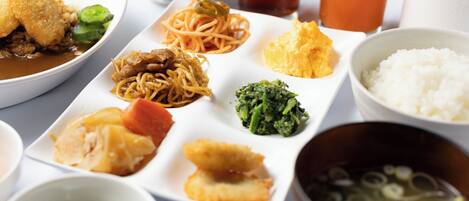 Diversos pratos, incluindo macarrão, arroz e sopa, servidos em um prato branco com vários acompanhamentos.
