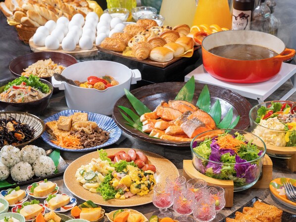 Verschiedene Speisen und Getränke auf einem Tisch, darunter Sushi, Salate und Brot.