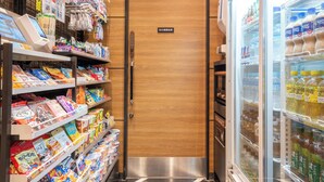 A grocery store interior with shelves stocked with snacks, a refrigerated section with beverages, and a wooden door with a sign. - APA Hotel Asakusa Kaminarimon Minami (Tokyo)