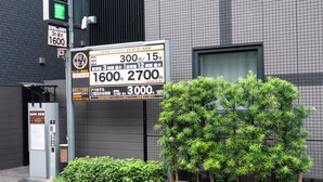 A parking sign with rates and a small tree in front of a building. - APA Hotel Asakusa Kaminarimon Minami (Tokyo)
