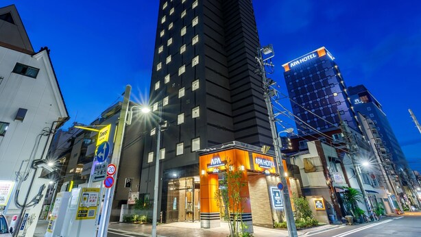 A modern hotel with a prominent sign, surrounded by other buildings and street signs. - APA Hotel Asakusa Kaminarimon Minami (Tokyo)