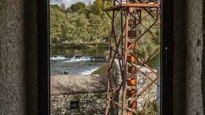 Une vue par la fenêtre sur une rivière, avec une structure métallique, des arbres et un ciel nuageux.