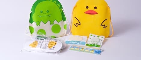 Two plush toys, one green and one yellow, with a small package and a toy train set in front.