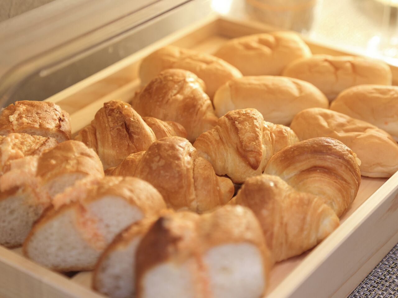 Verschiedene Backwaren, darunter Croissants und Brot, präsentiert in einer Holzkiste.