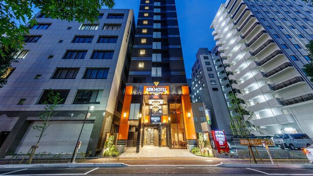 A modern hotel with a prominent ADA sign, surrounded by other buildings. - APA Hotel Hakata Ekimae 2chome (Fukuoka)