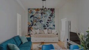 Una sala de estar moderna con un sofá, una mesa de comedor dispuesta para dos personas y un televisor sobre un mueble.