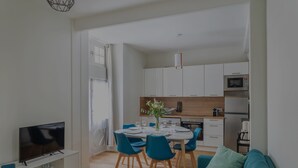 Una sala de estar moderna con televisor, sofá y comedor con sillas y una mesa.