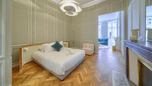 A spacious bedroom with a large bed, a sitting area, and a view of the city.