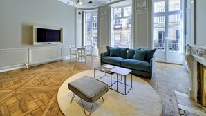 A spacious living room with a large window, a sofa, a TV, and a fireplace.