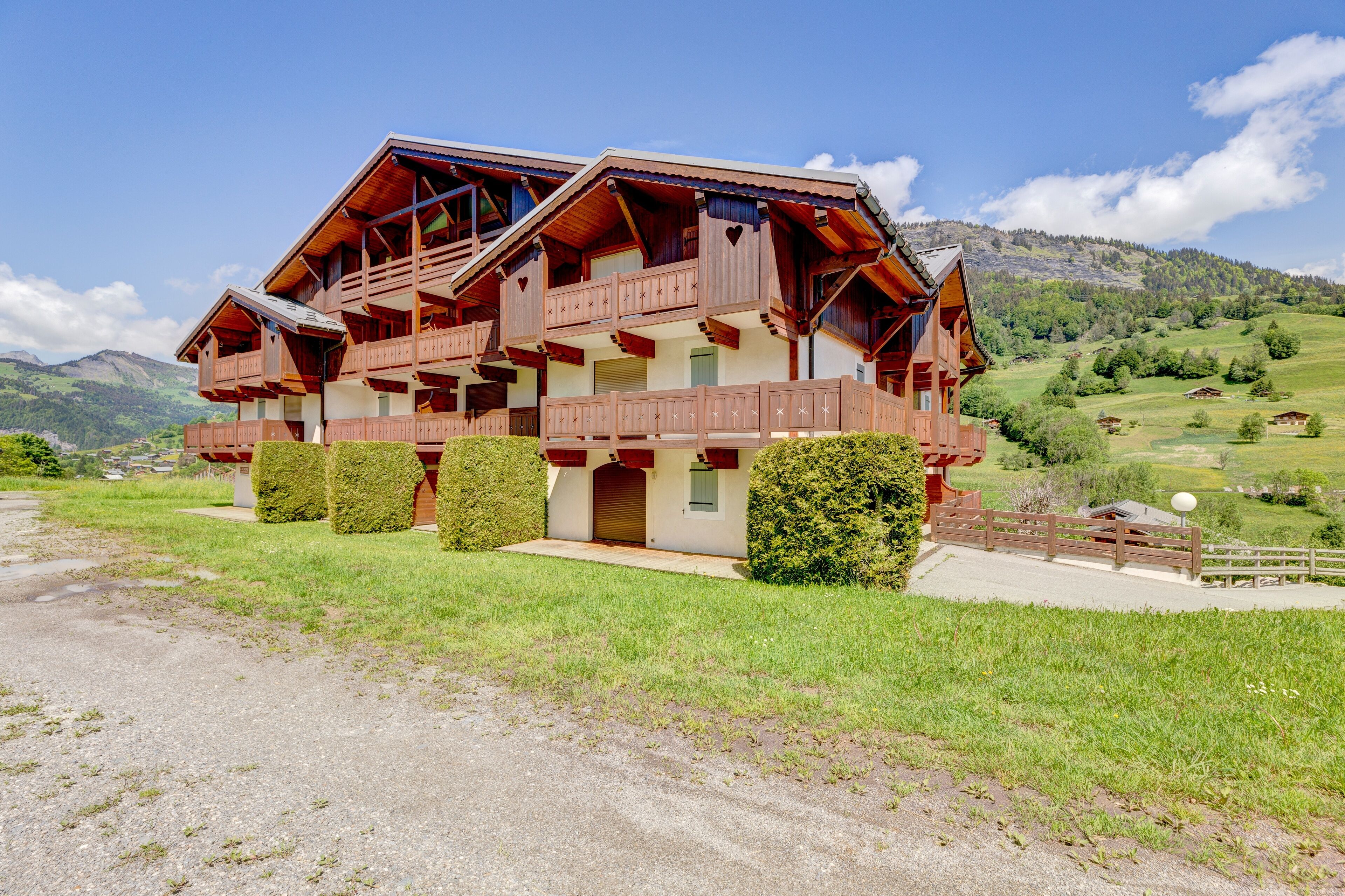 A chalet-style building with multiple balconies and a scenic mountain backdrop.