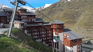 Et hotel med flere etager og balkoner, med et bjergrigt landskab i baggrunden.