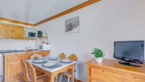 Et lille køkken med træskabe, en mikrobølgeovn, kaffemaskine og et spisebord til fire personer.